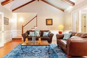A living room with a brown leather sofa, a coffee table, and a blue patterned rug.