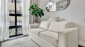 Een moderne woonkamer met een witte bank, een grote spiegel en een potplant.