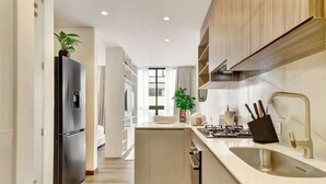 Een moderne keuken met een roestvrijstalen koelkast, een gootsteen met een moderne kraan en houten kastjes.