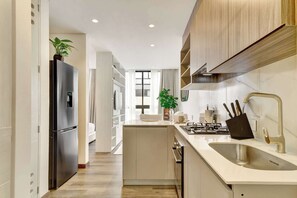 A modern kitchen with a stainless steel refrigerator, a sink with a modern faucet, and wooden cabinets. - w* | Luxury & Cozy Loft in Chapinero (Bogotá)
