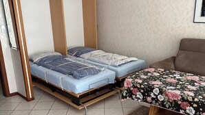 A bedroom with a bed, a sofa, and a wall-mounted TV.