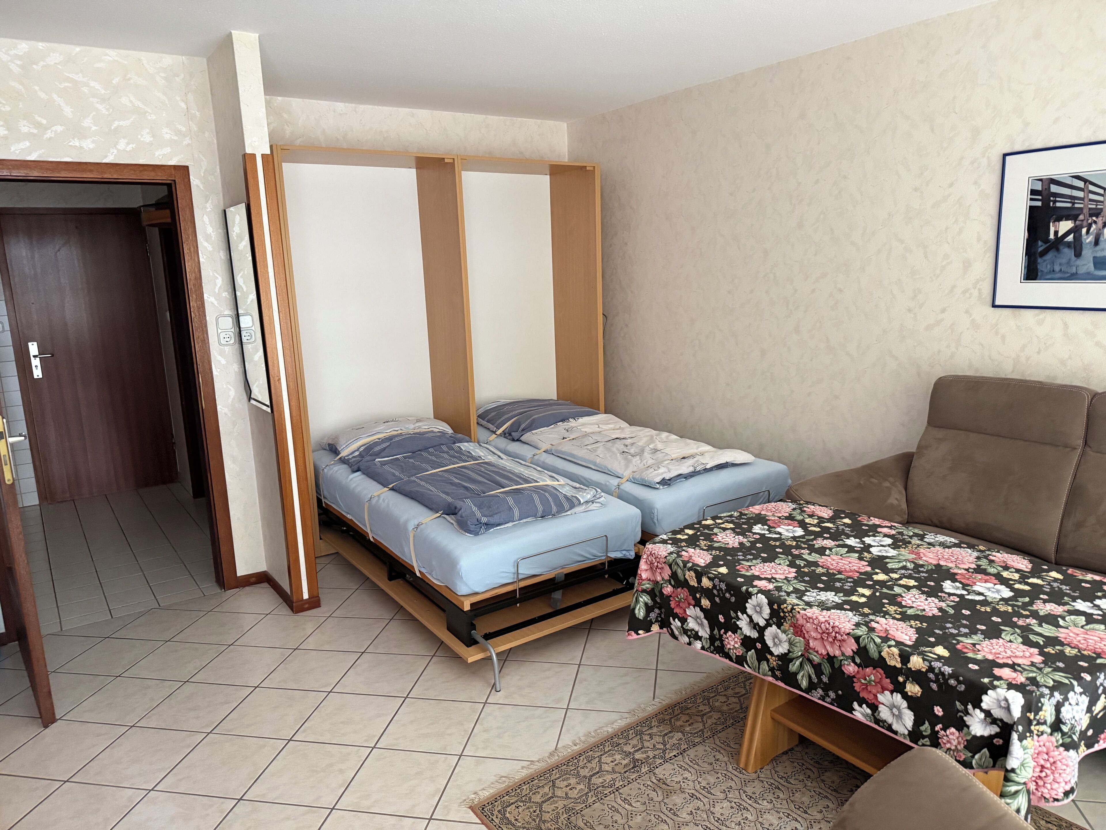 Una habitación con dos camas, un sofá, una puerta y un cuadro colgado en la pared.