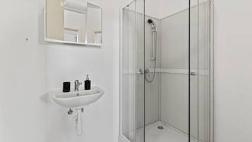 A bathroom with a white sink, a mirror, and a glass-enclosed shower.
