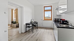 A modern kitchen with a window, a dining area with a table and chairs, and a view of the outdoors. - Faraway Homes Studios St.Michael (Liesingtal)