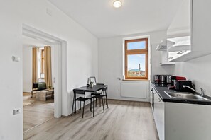 A modern kitchen with a window, a dining area with a table and chairs, and a view of the outdoors. - Faraway Homes Studios St.Michael (Liesingtal)