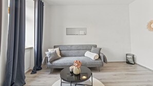 A modern living room with a grey sofa, a round black coffee table, and a small decorative vase. - Faraway Homes Studios St.Michael (Liesingtal)