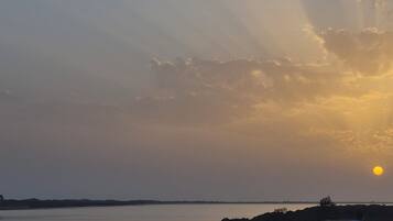 A sunset over a body of water with a rocky shoreline.