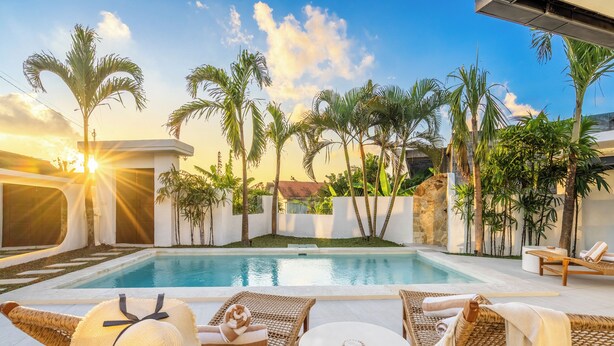 A poolside area with lounge chairs, a table, and a hat. - Villa AMARÉ New Stylish 3BR Canggu Large Pool,
Cinema & BBQ (Badung)