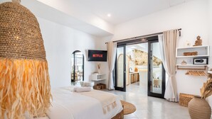 A modern hotel room with a large bed, a television, a sliding glass door to a balcony, and a minimalist decor. - Villa AMARÉ New Stylish 3BR Canggu Large Pool,
Cinema & BBQ (Badung)