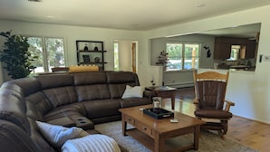 Ein modernes Wohnzimmer mit einem Ledersofa, einem Couchtisch aus Holz, einem Holzsesseln und einem großen Fenster.