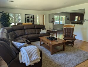 Ein modernes Wohnzimmer mit einem Ledersofa, einem Couchtisch aus Holz, einem Holzsesseln und einem großen Fenster.