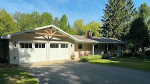 Ein eingeschossiges Haus mit Garage, überdachter Veranda und gepflegtem Rasen.