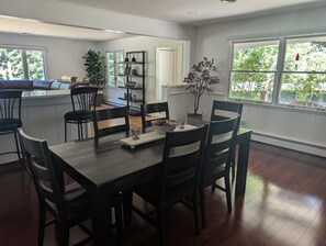 A dining area with a wooden table and chairs, a small plant, and a window with a view of greenery. - Newly Listed 3 Bedroom House in Suttons Bay Close to Downtown (Suttons Bay)
