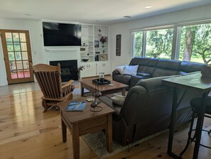 Ein modernes Wohnzimmer mit Kamin, einer Ledersofa, einem Holztisch und einem an der Wand montierten Fernseher.