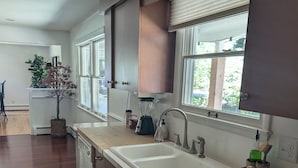 Eine moderne Küche mit doppelter Spüle, Holzschränken und einem Fenster mit Jalousien.