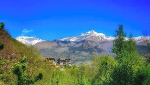 A mountain landscape with snow-capped peaks, a clear blue sky, and a house nestled among trees. - Belvedere House at the foot of the mountains, welcome our 4-legged friends (Gravere)