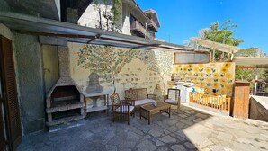 A stone patio with a built-in oven, wooden furniture, and a wall with a sunflower mural. - Belvedere House at the foot of the mountains, welcome our 4-legged friends (Gravere)