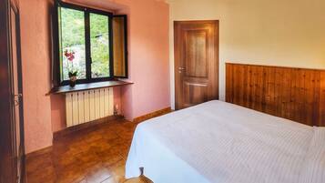 Ein Schlafzimmer mit einem Bett, einem Fenster mit Blick auf Grünflächen, einer Holztür und einer Heizung.