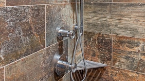 Eine Dusche mit Handbrause und einer wandmontierten Regendusche.