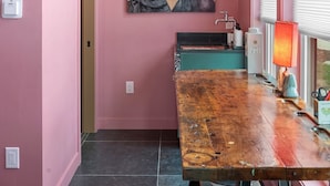 Ein Korridor mit rosafarbenen Wänden, einem Holztisch, einer Chandelüster und einem Gemälde von zwei Frauen.