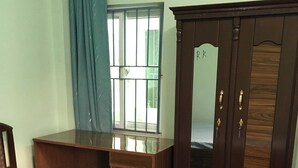 A bedroom with a bed, a wooden desk, a wardrobe, and a window with curtains. - Full Furnished 2BHK (Kathmandu)