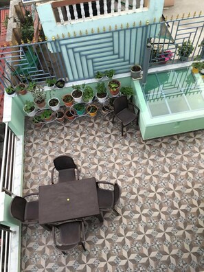 Una terraza en la azotea con zona de comedor, plantas en macetas y suelo estampado.