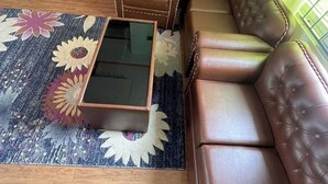 A living room with a brown leather sofa, a glass coffee table, and a patterned rug. - Full Furnished 2BHK (Kathmandu)