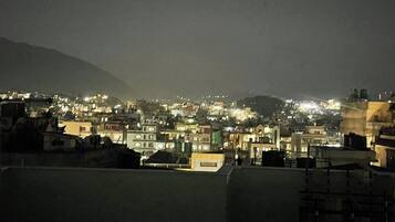 A nighttime cityscape with illuminated buildings and a mountain in the background.