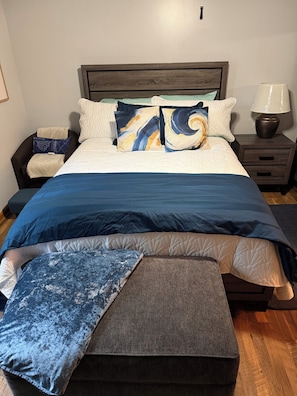 Ein Schlafzimmer mit einem Bett, Nachttischen, einer Lampe und einer Bank.