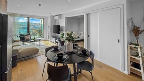 A modern dining area with a round table, chairs, and a vase of flowers. - Onehunga Sanctuary I 2-Bed Apt. I Amazing Views (Grey Lynn)
