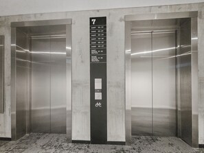 A modern elevator with a digital display indicating level 7, surrounded by metallic walls and a marble floor. - Onehunga Sanctuary I 2-Bed Apt. I Amazing Views (Grey Lynn)