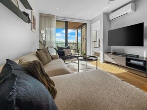 A modern living room with a sofa, coffee table, and TV. - Onehunga Sanctuary I 2-Bed Apt. I Amazing Views (Grey Lynn)