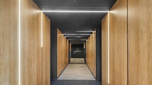 En modern hall med träpanel på väggarna, ett marmorgolv och takbelysning.