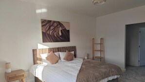 A bedroom with a bed, bedside table, lamp, and a painting on the wall. - Rothbury House, Luxury Family Retreat with Hot tub and Playframe (Nortumberland)