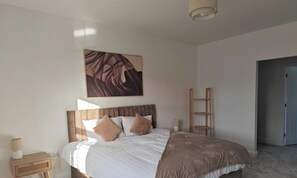 A bedroom with a bed, bedside tables, a wall-mounted artwork, and a door.
