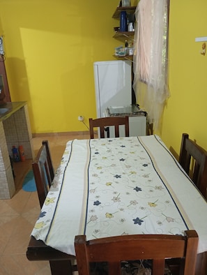 A small kitchen with a dining table, chairs, and a refrigerator.