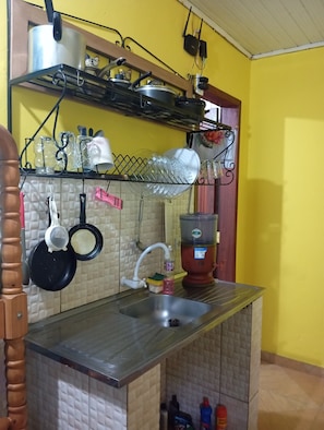A kitchen with a sink, a stove, and various utensils.