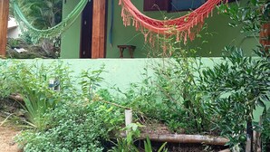 Een rustiek huis met een groene gevel, een hangmat en weelderige begroeiing eromheen.