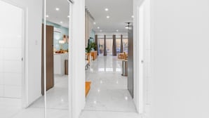 A modern hallway with a kitchen area visible in the background, featuring a marble floor and white walls. - Nirvana - Stay Steps from the Sand in Simpson Bay (Simpson Bay)