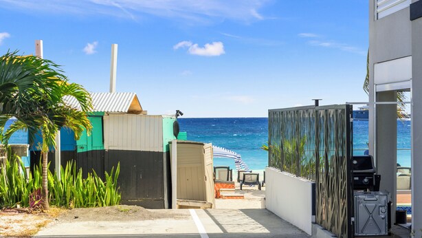 A coastal property with a beach view, a fenced patio, and a small building with a door. - Nirvana - Stay Steps from the Sand in Simpson Bay (Simpson Bay)