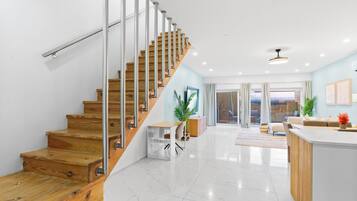 A modern interior with a wooden staircase, a kitchen area, and a living space with a view.