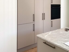 Eine Küche mit hellen Schränken, einem schwarzen Backofen und einer Marmorarbeitsplatte.