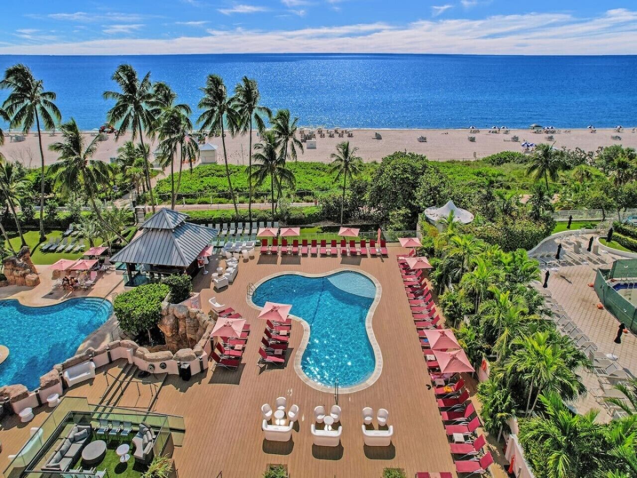 A resort with a large pool, lounge chairs, and a beach view.