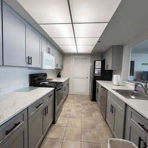 A modern kitchen with grey cabinets, a black refrigerator, a stove, and a sink. - Amazing view @ Long Beach Resort Tower-1 (Panama City Beach)