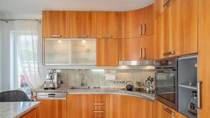 Een moderne keuken met houten kastjes, roestvrijstalen apparatuur en een granieten aanrecht.