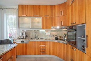 A modern kitchen with wooden cabinets, stainless steel appliances, and a granite countertop.