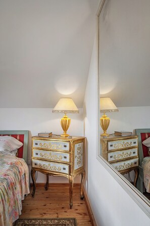 A bedroom with a bed, a dresser with drawers, a lamp, and a mirror.