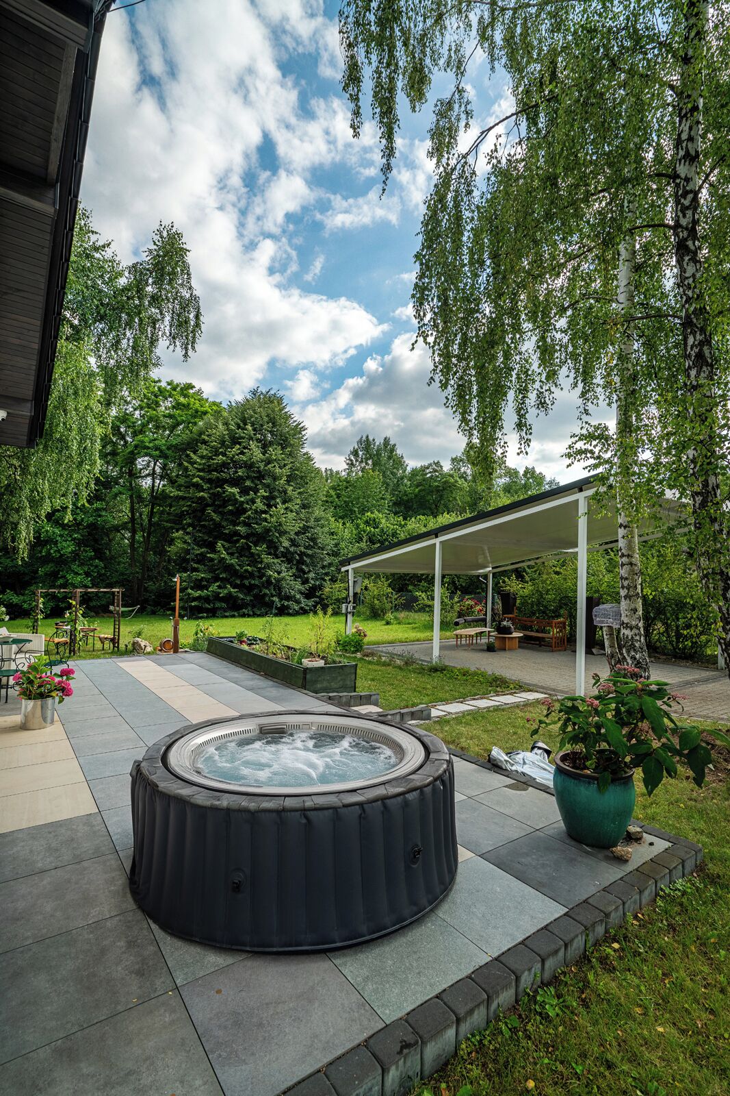 Puutarhassa on poreallas, ja sen yhteydessä on katettu oleskelualue sekä pergola.