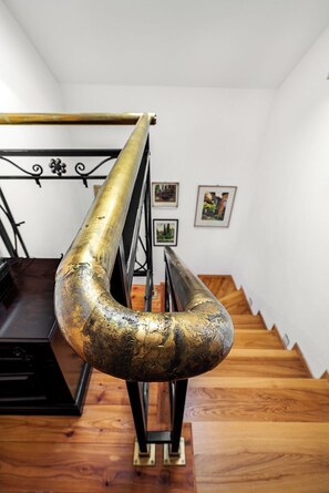 Una scala con una ringhiera metallica curva e particolare, e un corrimano in metallo nero.