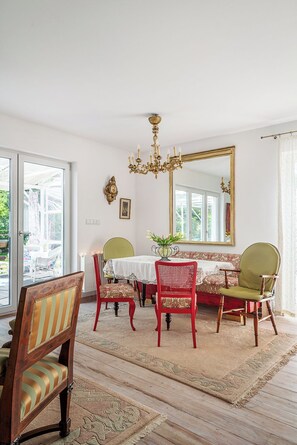 A dining room with a chandelier, a large mirror, and a view of the outdoors.